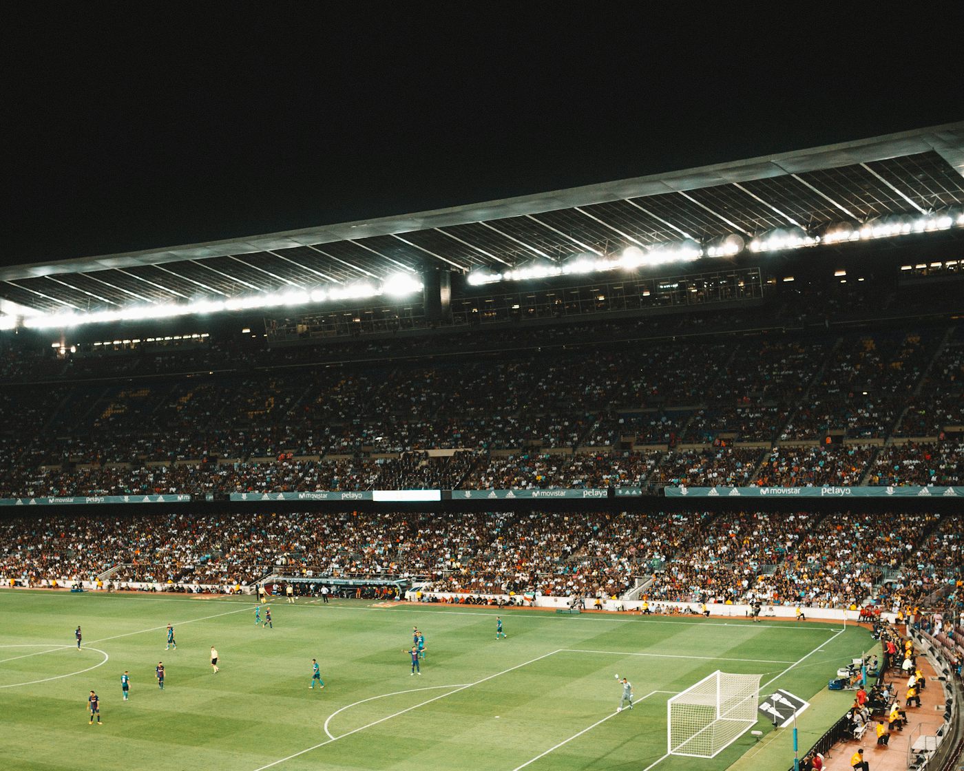 A floodlit pitch seen from a packed stand on a match night